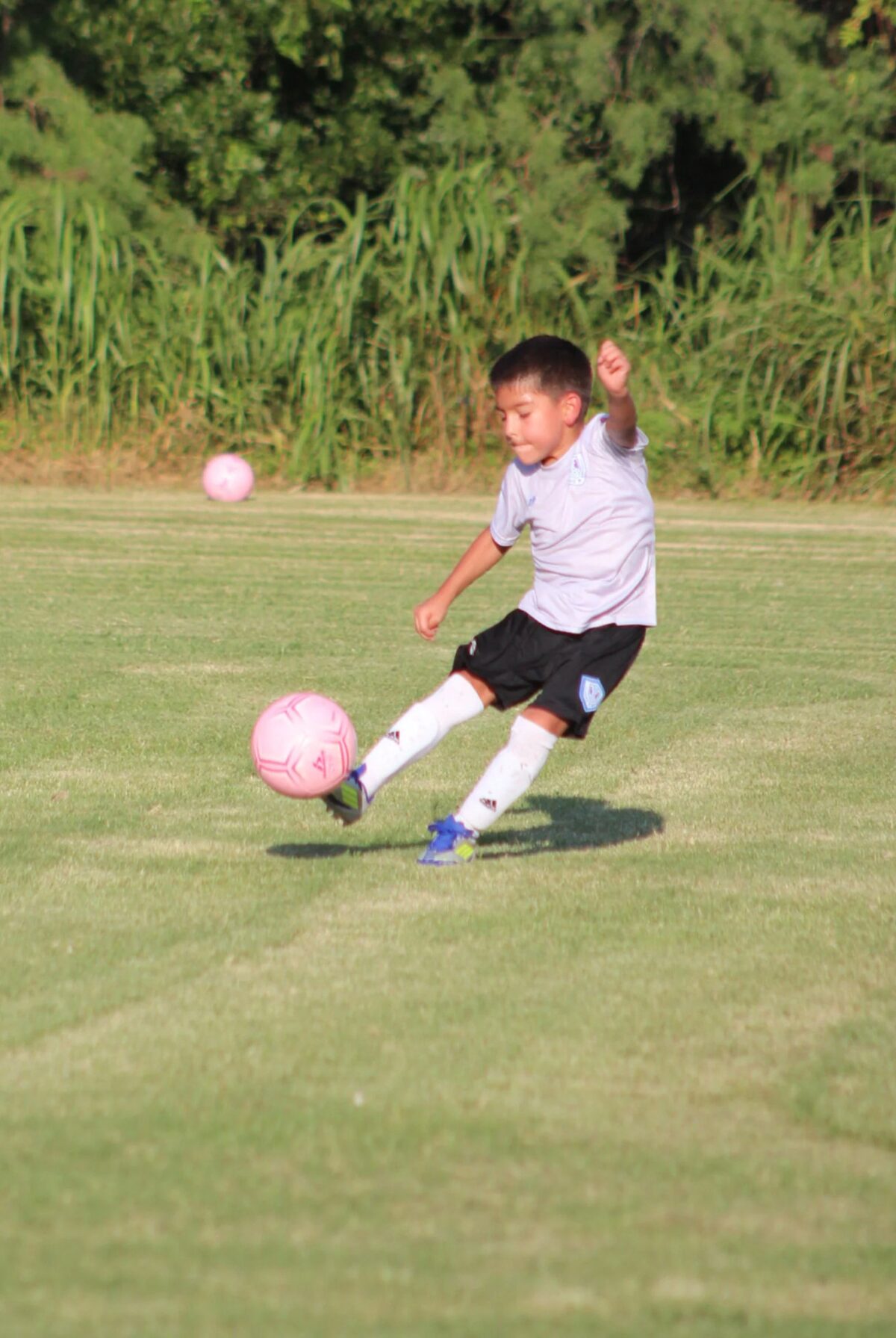 Un jugador pequeño rematando el balón en el campo de entrenamiento